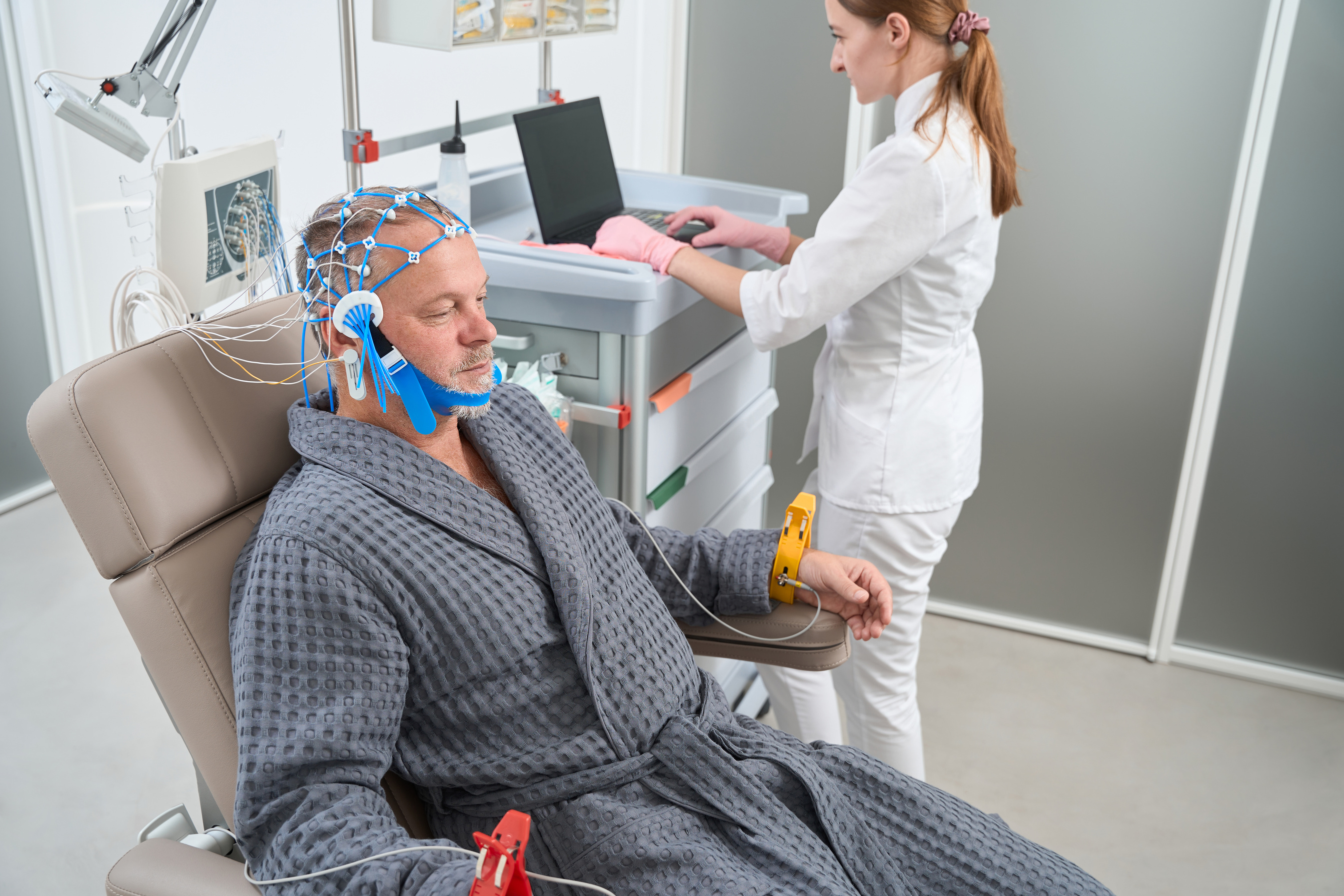 Man sits in medical chair with electrodes on his head