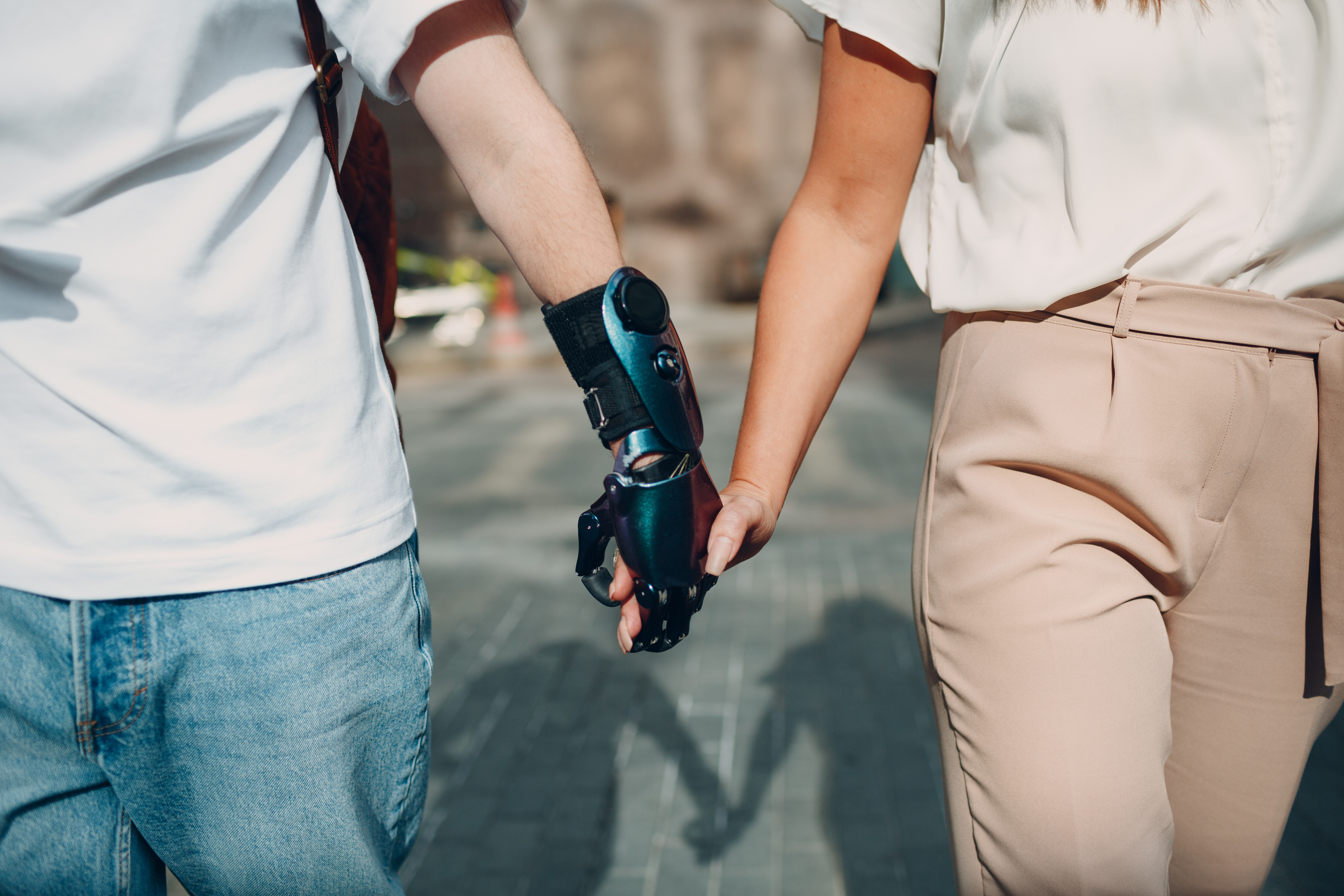 Young Disabled Man with Artificial Prosthetic Hand Walking and Holding Woman Girlfriend Hand.