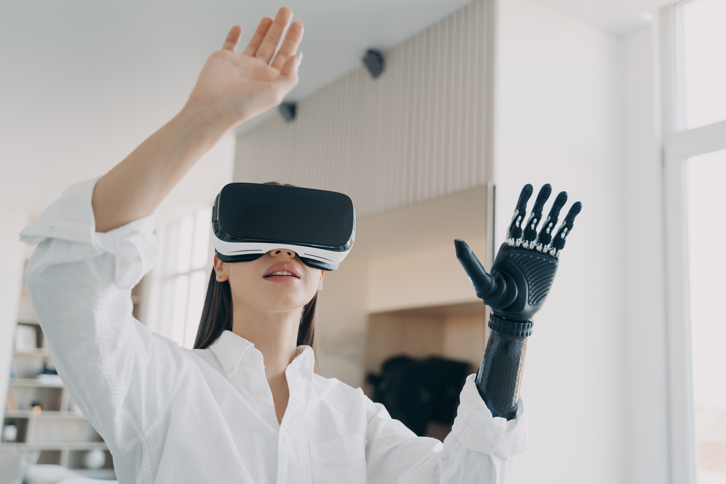 Modern disabled girl in VR glasses interacting with augmented reality, using bionic prosthetic arm